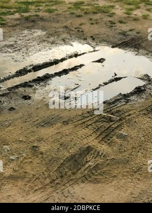 Flaques par temps pluvieux. Terrain boueux, route de terre après la pluie. Flaque et boue avec texture de chenille. Impassibilité des routes. Concept d'impuissance Banque D'Images