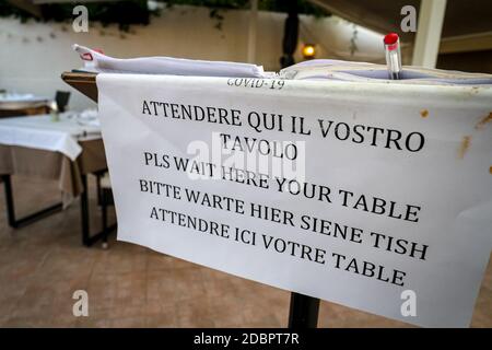 L'enseigne du restaurant informe les clients qu'ils doivent attendre d'être assis dans différentes langues, ce qui garantit la prise de distance sociale pendant la pandémie du coronavirus. Banque D'Images