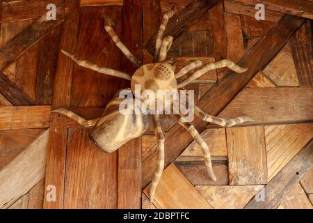 Grande tarantula sur le mur de planches rabotées. Statue énorme araignée en bois. Araignée jouet brune sur le plancher en bois. Mise au point sélective. Banque D'Images