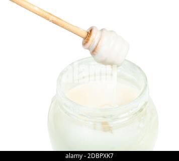 bâton de bois avec du miel blanc naturel organique goutte à goutte sur verre pot avec miel isolé sur fond blanc Banque D'Images