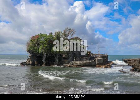 Des vagues se brisent sur une falaise au sommet de laquelle se trouve le temple hindou de Tanah Lot. Temple construit sur un rocher dans la mer au large de la côte de l'île de Bali, Indones Banque D'Images