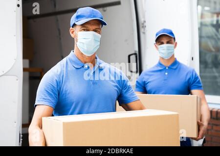 Blue Delivery Men déchargement du paquet du camion avec masque facial Banque D'Images