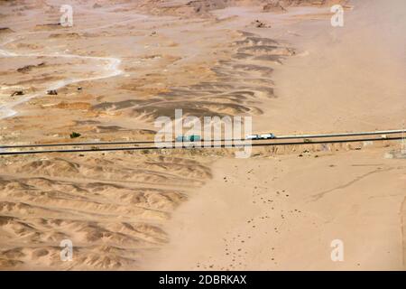 Belle vue sur la route asphaltée dans les terres de sable sauvage du désert. Vue aérienne sur les paysages de l'autoroute traversant le désert. Tir de drone depuis le dessus du désert Banque D'Images