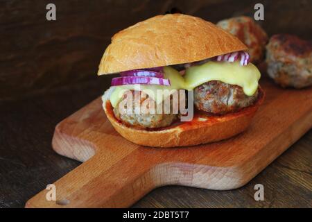 Sous-sandwich au meatball épicé fait maison avec sauce marinara et fromage sur planche à découper. Fond sombre . Banque D'Images