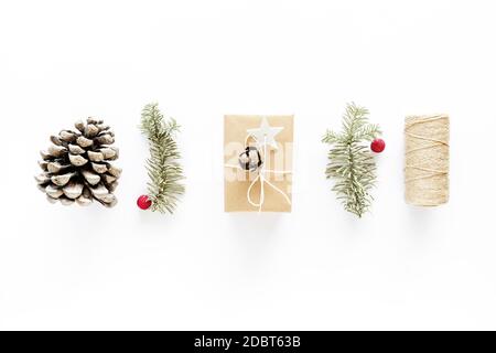 Composition d'art cadeau de Noël sur surface blanche. Cadeaux, décorations de noël en bois, branches de sapin, cône de pin. Concept de bricolage fait à la main. Plat, dessus Banque D'Images