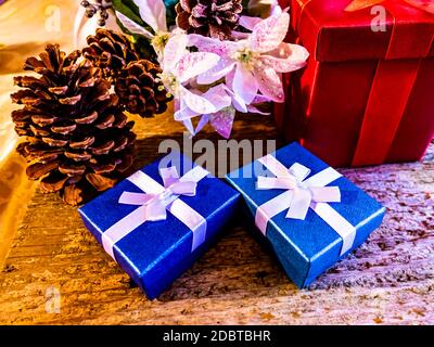 Une vie de Noël encore de petits cadeaux enveloppés de couleur avec des rubans blancs et de grands cônes de pin sur une table Banque D'Images