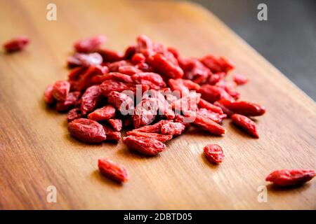Baies de Goji sur une planche à découper en bois Banque D'Images