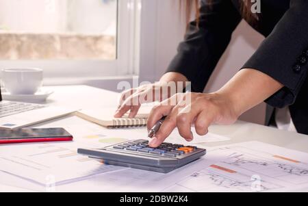 Gros plan des femmes utilisant des calculatrices pour créer des rapports comptables par fenêtre dans leurs propres maisons, concepts de calcul des coûts et concept de travail à domicile Banque D'Images