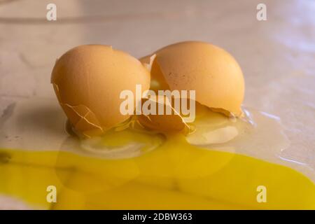 Découper un jaune et un blanc d'œuf cassé avec la coquille écrasée sur un comptoir de cuisine en gros plan Banque D'Images