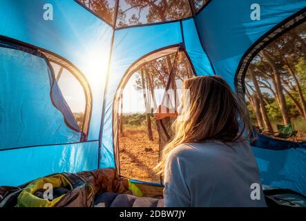 Matin dans la tente, jeune femme se réveilla et regarde l'incroyable beauté de la nature. Camping dans la forêt montagneuse. Holi d'été actif Banque D'Images