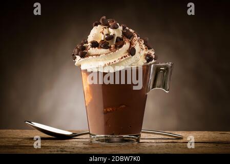 Tasse de café avec crème fouettée, poudre de cacao et copeaux de chocolat. Banque D'Images