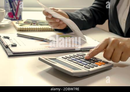 Les femmes d'affaires qui utilisent leurs doigts pour appuyer sur la calculatrice pour calculer les factures au bureau. Banque D'Images
