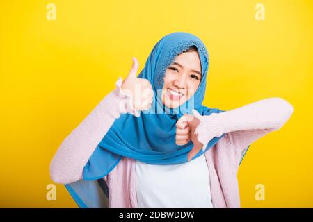 Asiatique musulman arabe, Portrait de la bonne belle jeune femme Islam religieux porter voile hijab sourire drôle elle montrant les pouces vers le haut et les pouces vers le bas difficile Banque D'Images