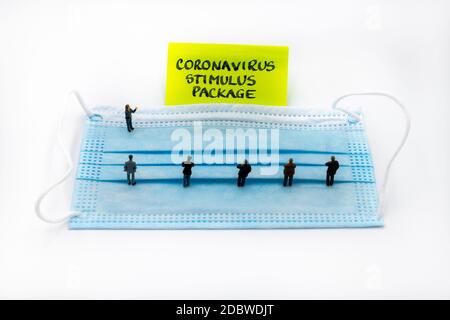 Figurines miniatures posées comme des gens d'affaires se tenant socialement distancé sur le masque médical lors d'une réunion regardant post-it note avec coronavirus St Banque D'Images