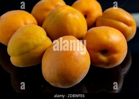 Une pile d'abricots épars se trouve avec réflexion sur un verre noir Banque D'Images