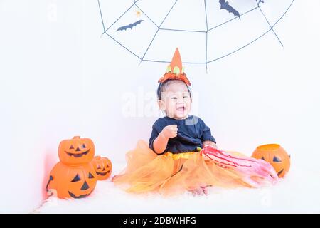 Drôle heureux petite fille mignon bébé en costume d'Halloween avec citrouille Jack avec Cobweb et ballon noir dans la maison Halloween fête sur mur blanc backgroun Banque D'Images