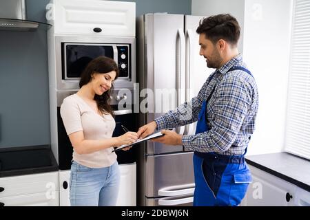 Bonne cliente femme signant la facture du plombier en interne Banque D'Images