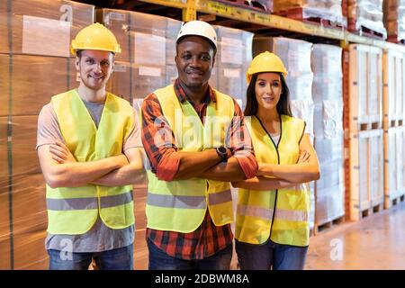 Portrait african Black Warehouse Supervisor stand et a traversé ses bras avec son équipe interraciale dans le grand centre de distribution d'entrepôt. Logiciels professionnels Banque D'Images