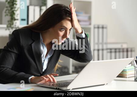 Surprise femme de direction découvrant une erreur sur un ordinateur portable assis sur un bureau Banque D'Images