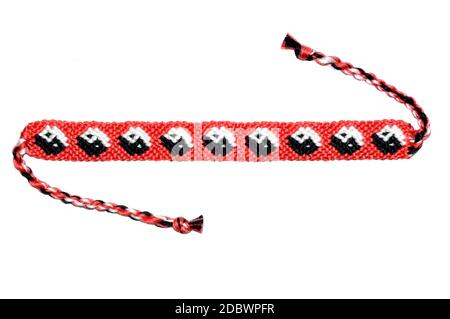 Bracelet d'amitié tissé rouge avec motif Yin et yang fait à la main de broderie fil brillant avec des noeuds isolés sur blanc arrière-plan Banque D'Images