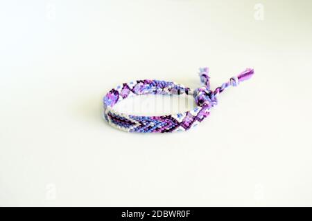 Mise au point sélective d'un bracelet d'amitié tissé avec des couleurs vives motif fait à la main de fil isolé sur fond blanc Banque D'Images