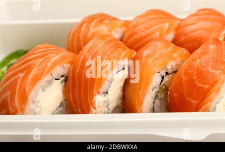 Gros plan à emporter avec six petits pains à sushis Philadelphia et saumon cru dans un plateau en plastique jetable, vue en grand angle Banque D'Images