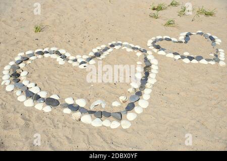 Un grand coeur en pierres et coquillages blancs à côté du petit coeur sur la plage de la mer japonaise. Banque D'Images