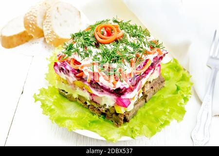 Salade fraîche avec bœuf, pommes de terre bouillies, poires, carottes coréennes épicées, assaisonnées de mayonnaise et garnies d'aneth sur la laitue verte dans l'assiette, pain Banque D'Images