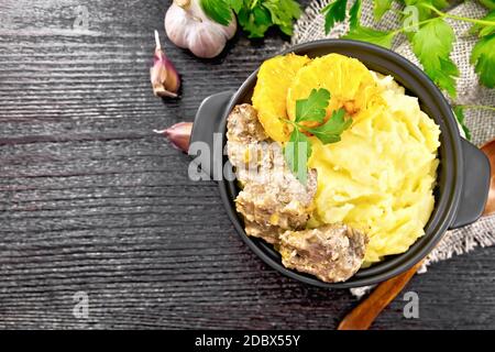 Poulet rasé avec des oranges, de la crème sure, de la sauce soja et des herbes de Provence dans une petite casserole avec purée de pommes de terre sur la serviette de saumurier, une cuillère et du persil Banque D'Images