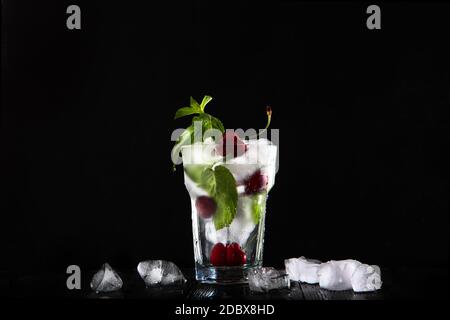 Limonade à la cerise dans un grand verre avec glace. Photo sur fond noir. Boisson d'été en saison. Photo sur fond noir. Copier l'espace.vue de dessus. Banque D'Images