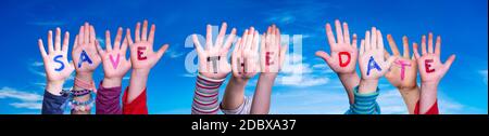 Enfants mains construire coloré Anglais Word Enregistrer la date. Ciel bleu comme arrière-plan Banque D'Images