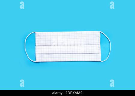 Masque en tissu blanc fait main sur fond bleu. Vue de dessus Banque D'Images