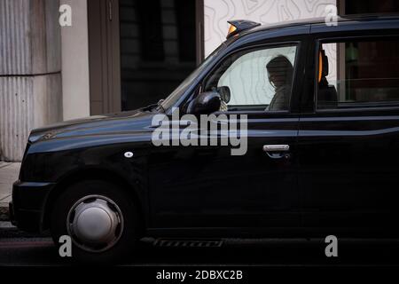 Un chauffeur apparemment endormi dans un taxi noir faisant la queue pour un billet devant la gare Victoria, Londres. Les chauffeurs de taxi londoniens sont confrontés à de longues attentes pour un aller simple après que l'industrie ait connu une forte baisse de la demande, car les restrictions du coronavirus continuent de réduire les déplacements et le travail au bureau. Banque D'Images