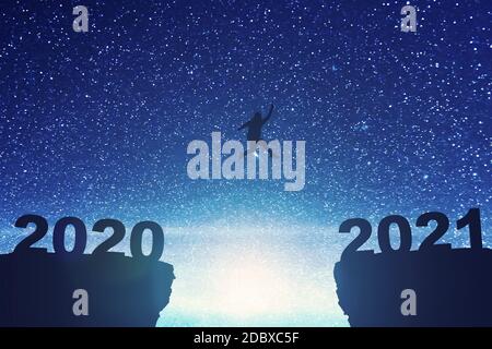 Silhouette de l'homme gras sautant de la colline 2020 à la colline 2021 avec arrière-plan de scène de nuit. Bonne année 2021 Banque D'Images