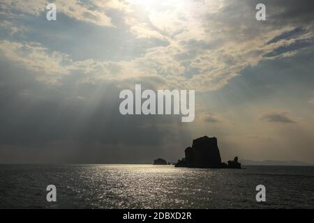 Les rayons du soleil qui brille sur petite île déserte dans la mer d'Andaman près de Phi Phi, montrant seulement silhouette de rock. Ao Nang, Thaïlande Banque D'Images