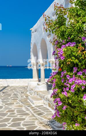 Allée cycladitique traditionnelle avec rue étroite, église blanchie à la chaux et fleurs à parikia, île de Paros, Grèce. Banque D'Images