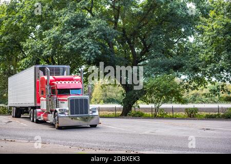 Camion semi-remorque classique rouge avec beaucoup de poli accessoires chromés et tuyaux verticaux chargés réfrigérateur semi-remorque debout sur la zone de repos p Banque D'Images