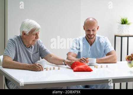 Senior jouant Lotto avec soignant à la maison Banque D'Images