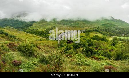 Glenfinnan viaduc de chemin de fer (l'emplacement de film Harry Potter), temps couvert avec le ciel gris et beaucoup d'herbe verte et des arbres autour. Inverness, Scotl Banque D'Images