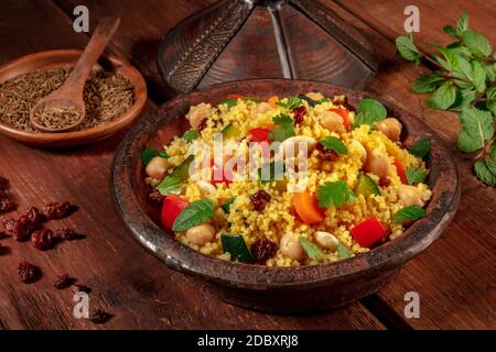 Couscous marocain dans un tagine avec des ingrédients dans un noir arrière-plan rustique en bois Banque D'Images