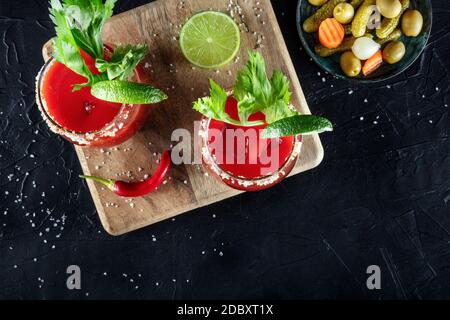 Bloody Mary cocktails, plan d'écran plat avec un endroit pour le texte. Les boissons sont servies avec du citron vert, du céleri et des cornichons Banque D'Images