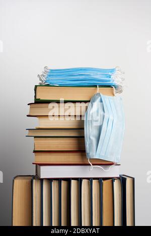 pile de divers livres et masques médicaux jetables sur fond blanc, concept de visite de bibliothèques dans l'équipement de protection individuelle pendant la quarantaine Banque D'Images