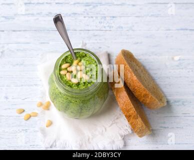 Sauce pesto maison fraîche à l'arugula avec pignons de pin dans un pot en verre sur fond de bois bleu. Une nourriture saine et délicieuse. Mise au point sélective Banque D'Images