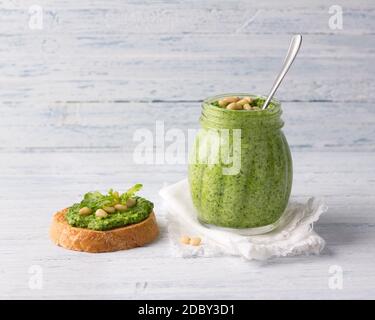 Sauce pesto maison fraîche à l'arugula avec pignons de pin dans un pot en verre sur fond de bois bleu. Une nourriture saine et délicieuse. Mise au point sélective Banque D'Images