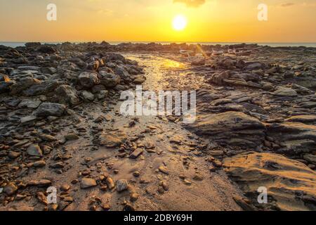 Plage de rochers et de découverte à marée basse avec ses bateaux sur la terre ferme en arrière-plan pendant le coucher du soleil du soir lumière arrière. Koh Lanta, Thaïlande Banque D'Images