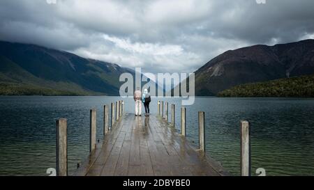 Couple debout sur le quai du lac Rotoiti après la pluie, parc national Nelson Lakes Banque D'Images