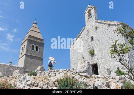 Visite d'une femme dans un ancien village costal de Lubenice sur l'île de Cres, Croatie. Banque D'Images