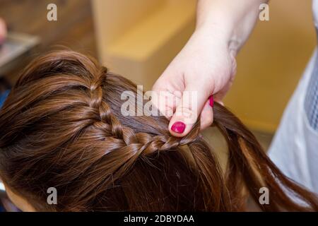 Tresse professionnelle de tresses par un coiffeur principal dans un salon de beauté. Le concept de soins capillaires. Banque D'Images