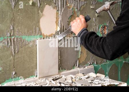 Préparation de réparer la salle de bain. L'homme dépose de tuiles anciennes. Banque D'Images