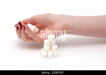 La main féminine holding pile de cubes de sucre blanc Banque D'Images